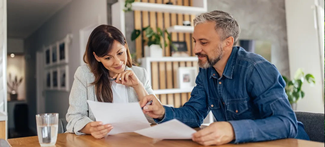 Pareja revisando documentos juntos sentados en el salón de una casa
