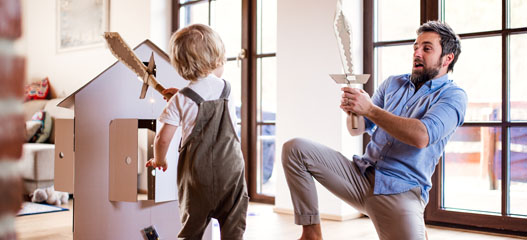 padre e hijo jugando con espadas de cartón en casa